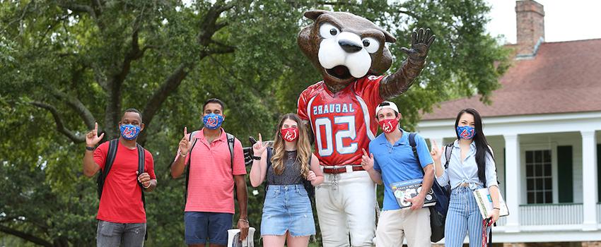 Students holding up J signs in front of Southpaw statue.